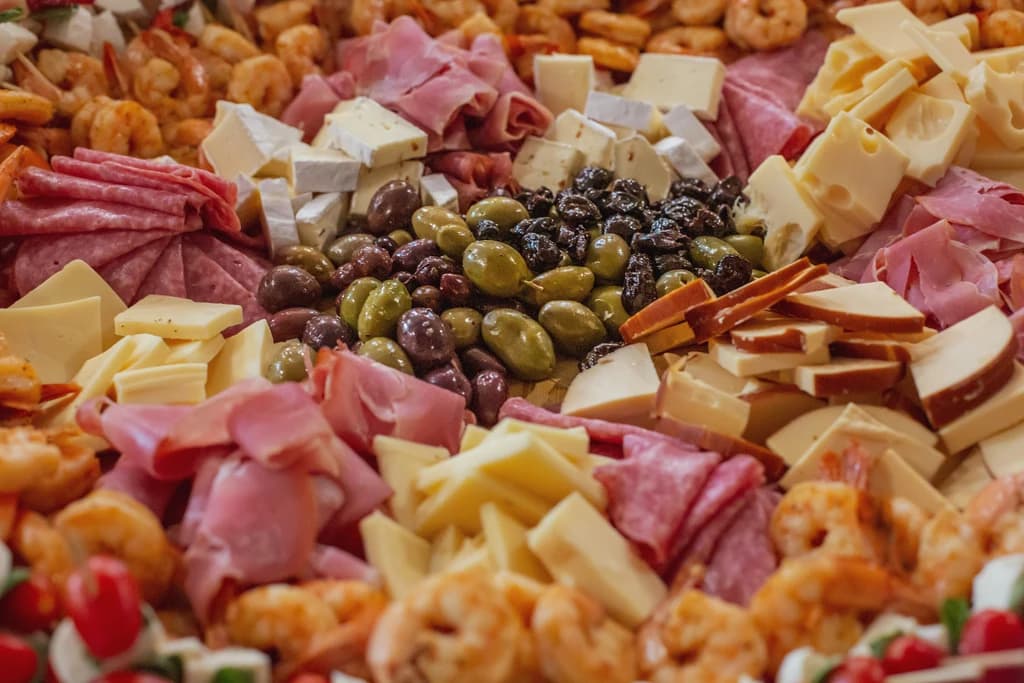 different cheeses, meats, and olives on a board