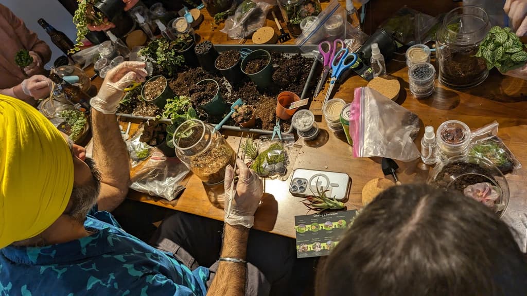 Participants working on their succulent ornaments at a table filled with plants, tools, and decorative materials.
