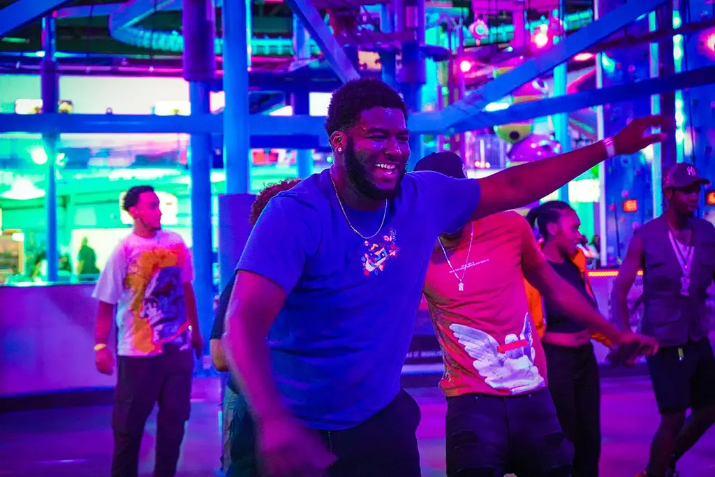 a group of people dancing in a room with neon lights