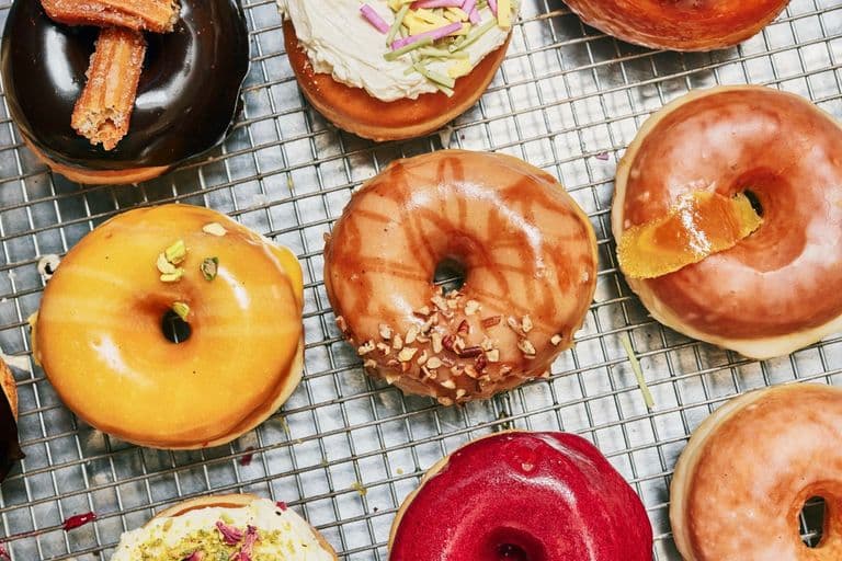 Close ups of assorted donuts in vibrant colors with a variety of toppings.