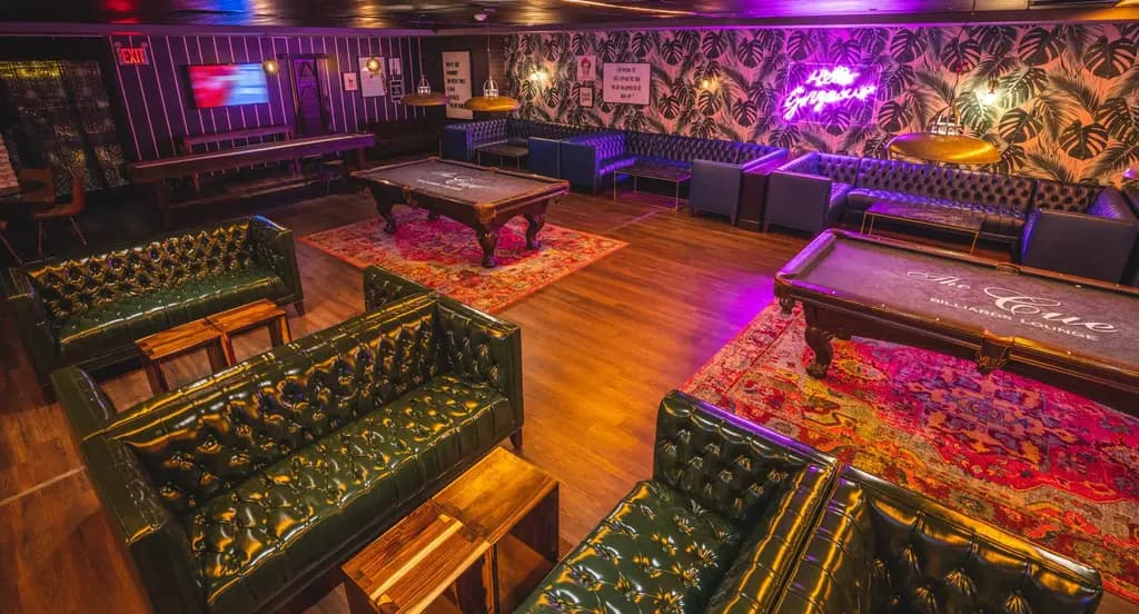 a pool hall with leather pool tables and seatings areas with leather couches and coffee tables around them