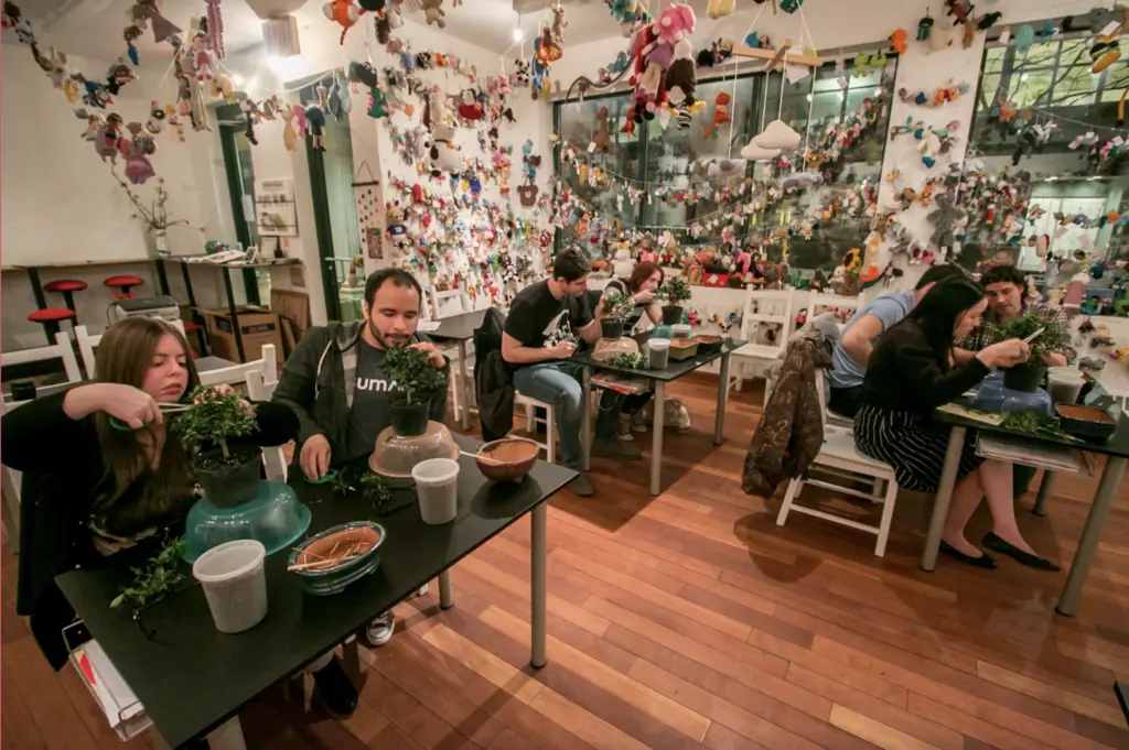 people sitting at tables making bonsai trees