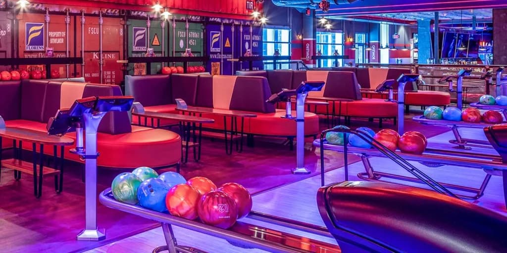 A modern bowling alley with vibrant lighting and multiple lanes, filled with people enjoying a night of bowling.
