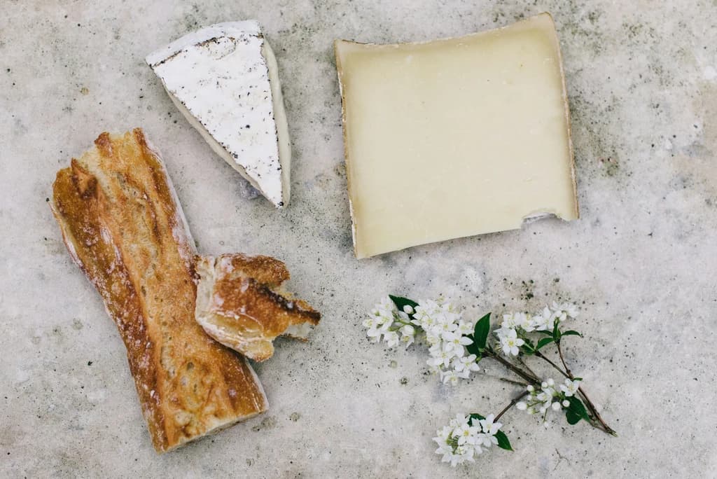 different cheeses and a baguette on a counter