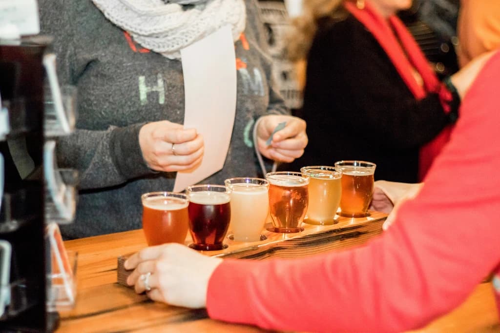 a flight of ciders on a table between a group of people