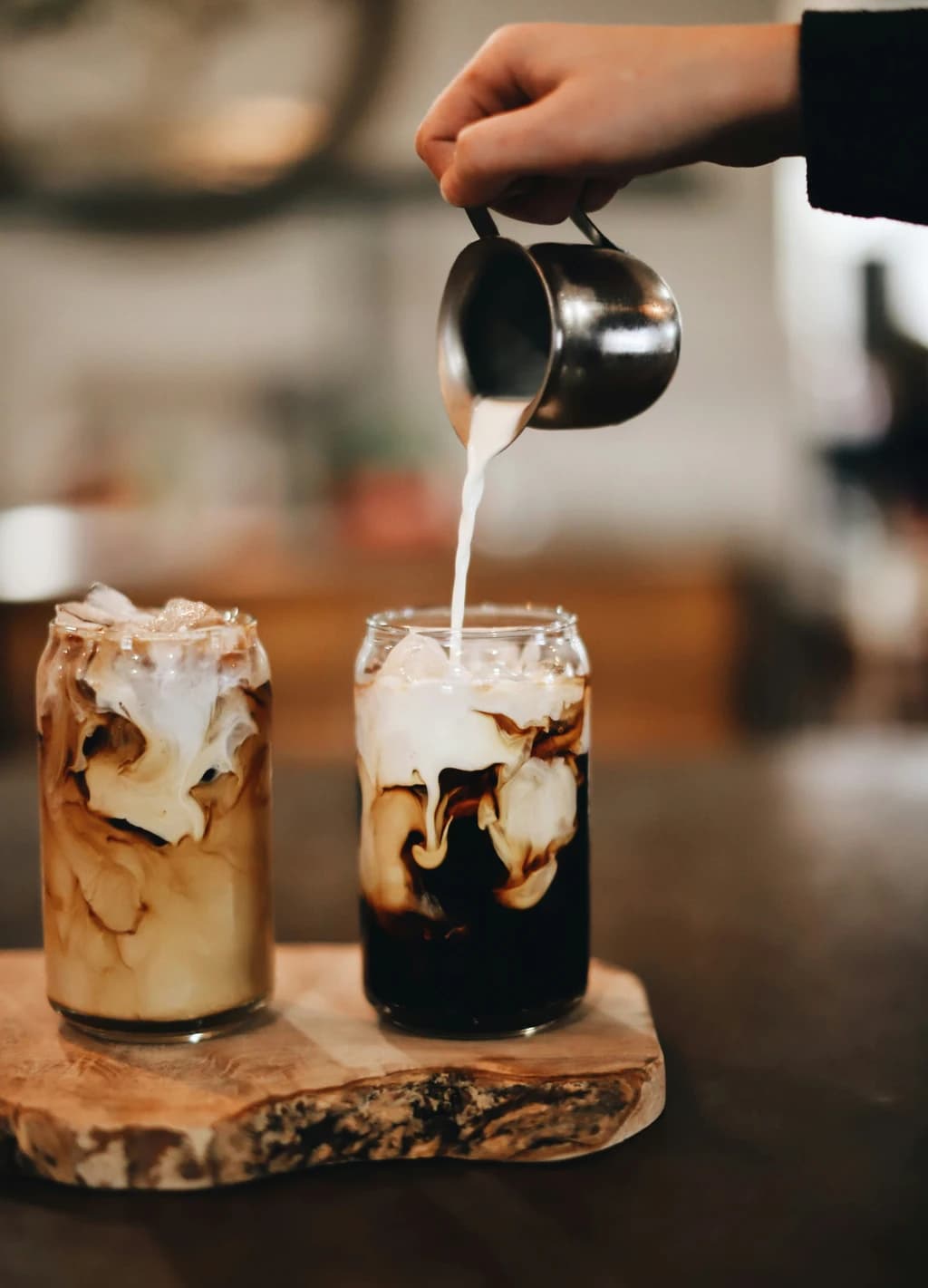somone pouring milk into a cold brew coffee