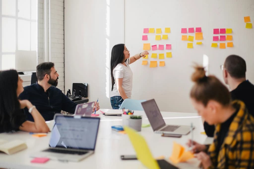 a person in front of a group with sticky notes on a board behind them