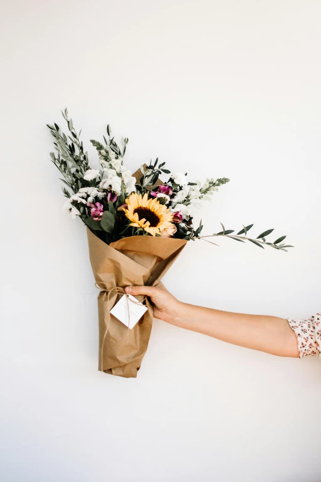 someone holding a bouque of flowers wrapped in brown paper
