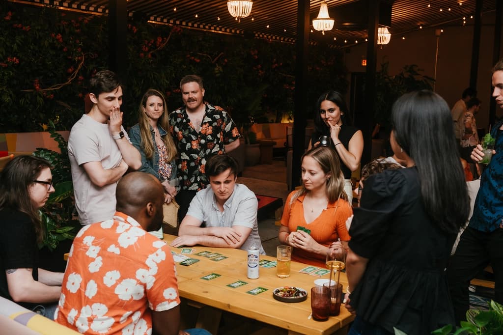 A lively group of people playing a strategic board game in a well-lit room with large windows.