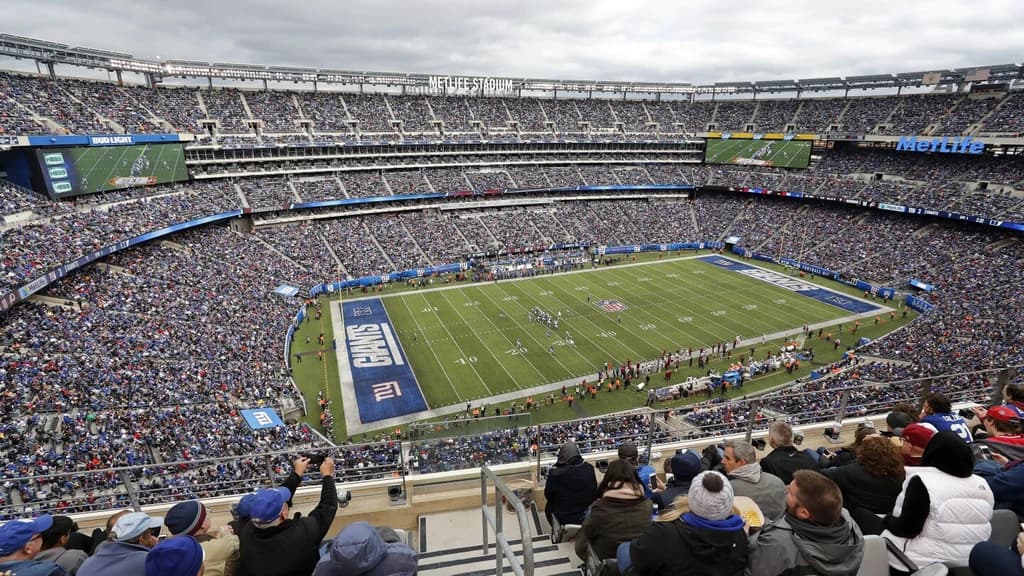 Packed MetLife Stadium during a New York Giants game, with fans filling the stands and the game in action on the field.