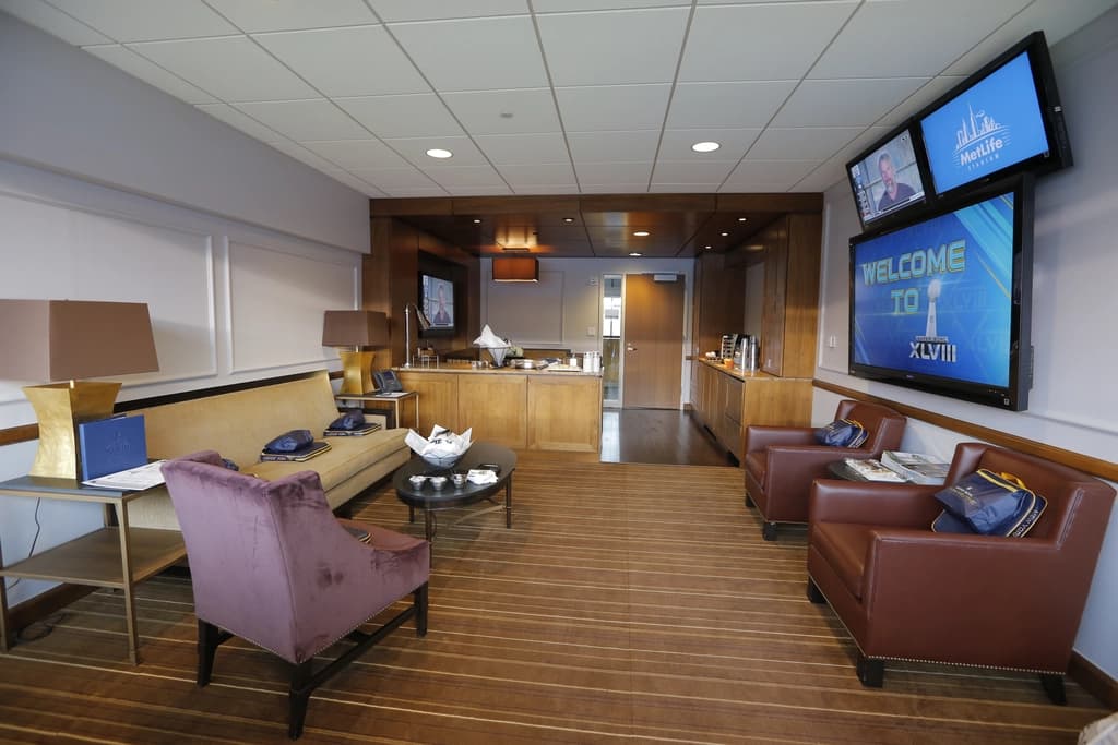 Luxurious suite at MetLife Stadium with comfortable seating, a bar area, and multiple screens, providing an exclusive viewing experience.