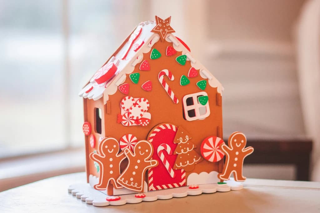 A festive gingerbread house with white icing and candy decorations, complete with gingerbread figures and candy canes.