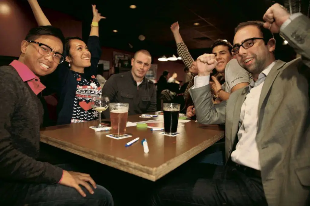 Group celebrating a trivia win with raised hands