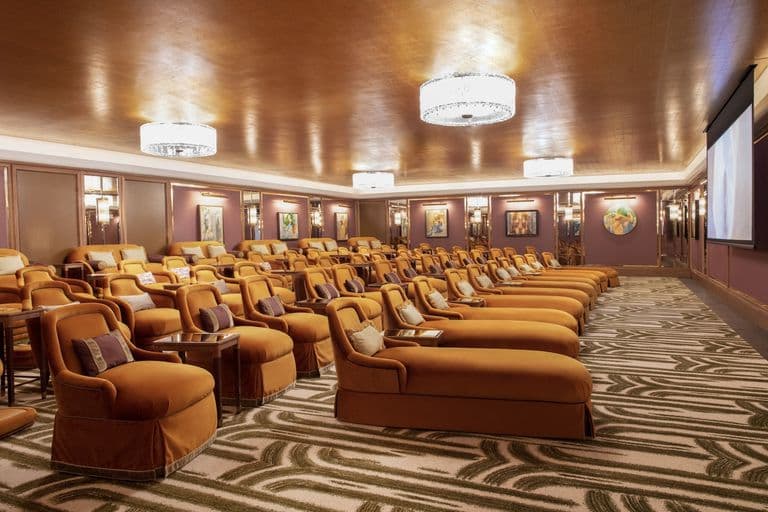Luxurious private screening room with plush gold seating, gold-leaf ceiling, and Art Deco carpet.