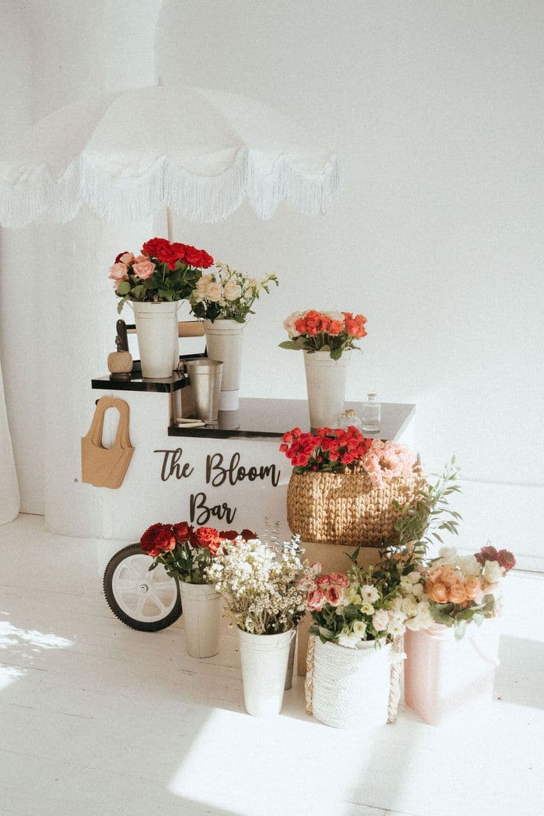 Mobile flower cart with pastel and red blooms in white buckets, styled for a floral pop-up experience indoors.