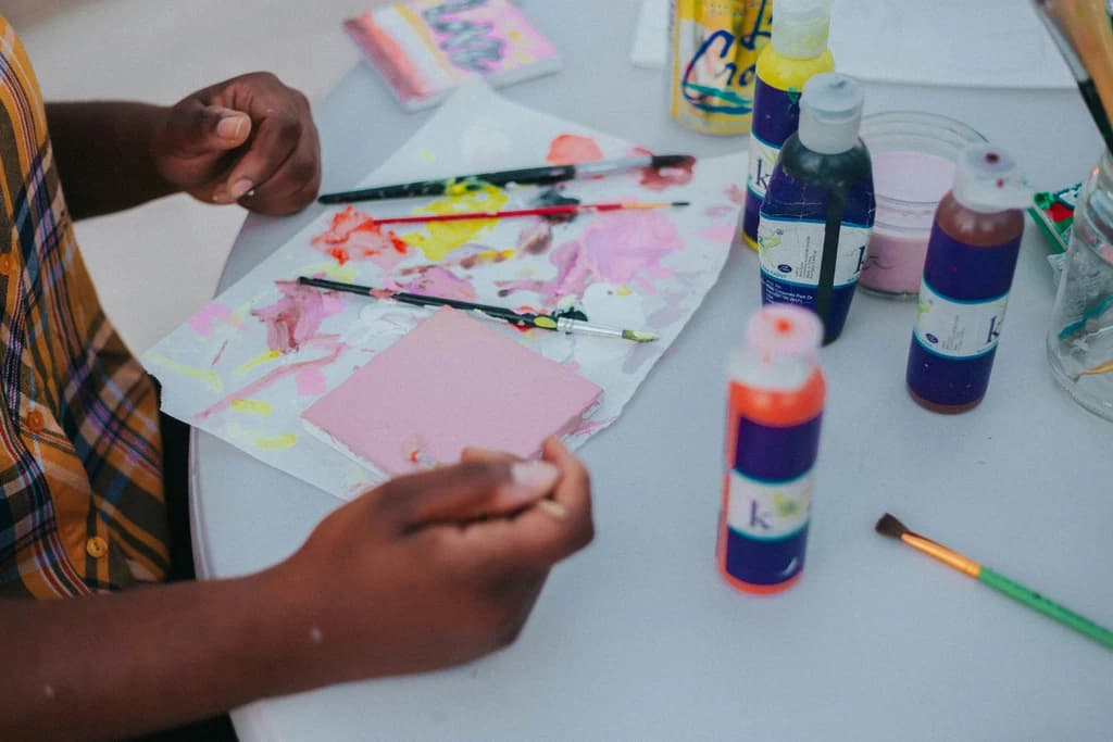 a kid with paints and paper in front of them on a table
