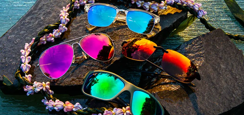 different sunglasses on a rock with a flower necklace around them