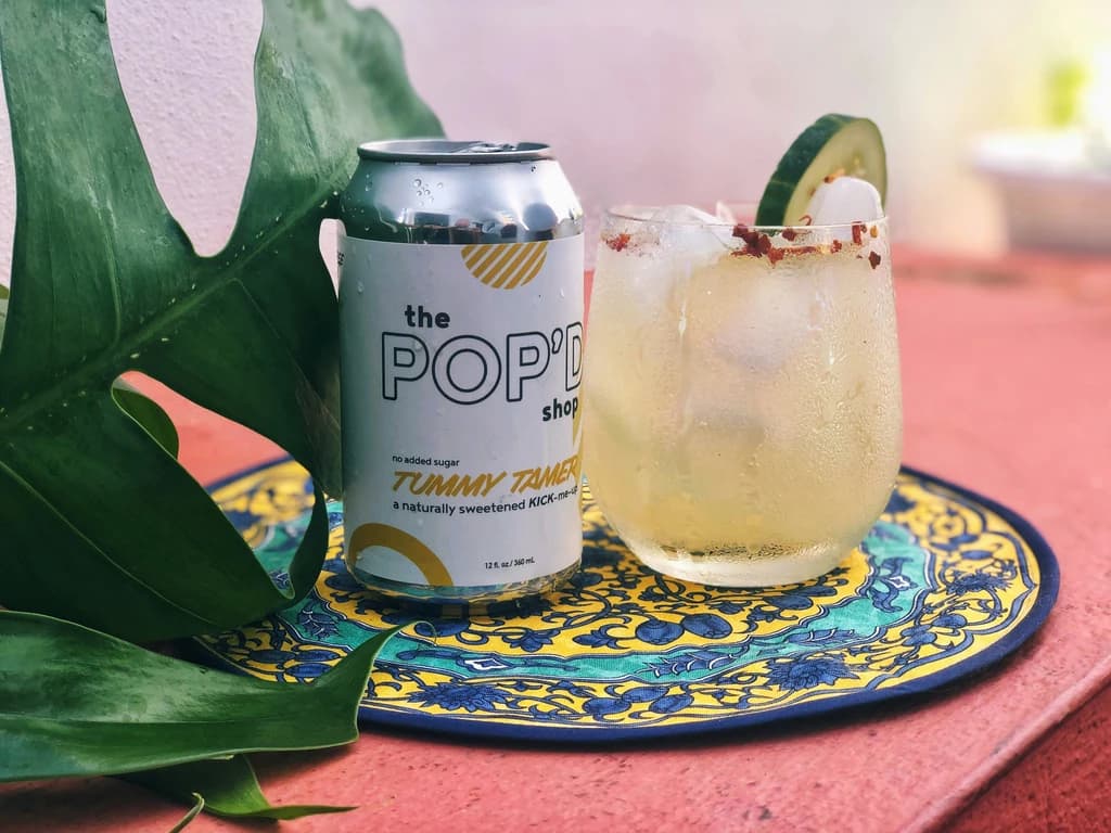 a  drink with cucumber and spices, with a can of soda next to it