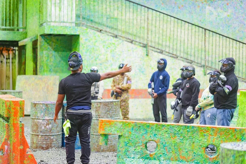 people standing in a paintball field listening to instructions