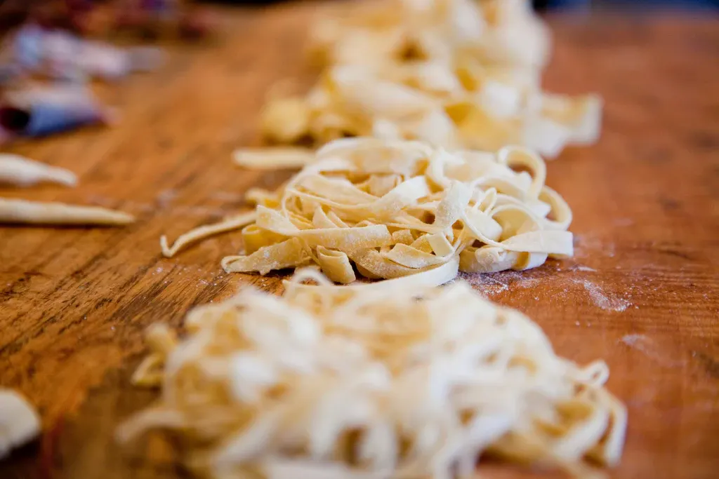 a person putting seasoning on pasta in a large pot