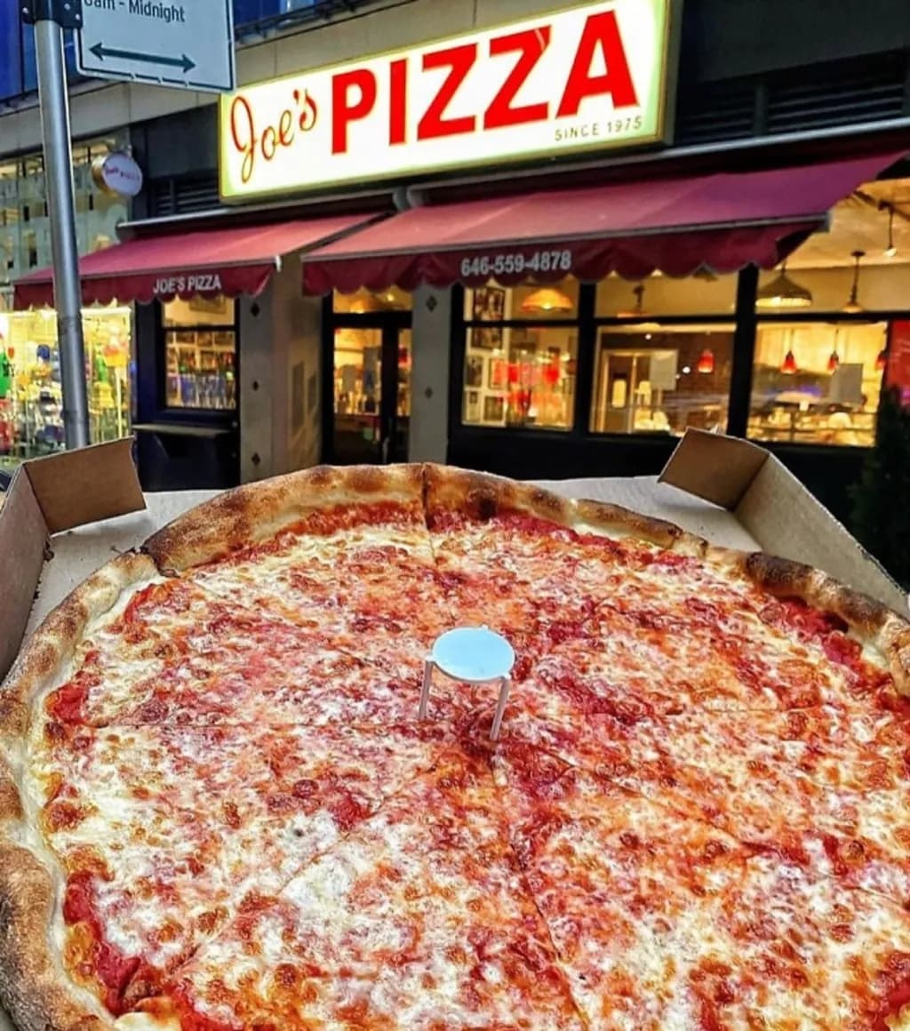 a cheese pizza in front of a pizza parlor