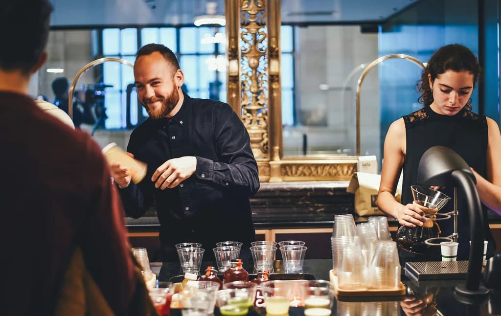Bartender shaking a drink with a woman preparing a cocktail nearby