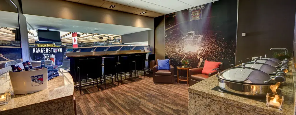 Private suite at Madison Square Garden overlooking the ice, with high-top seating and a catering setup.