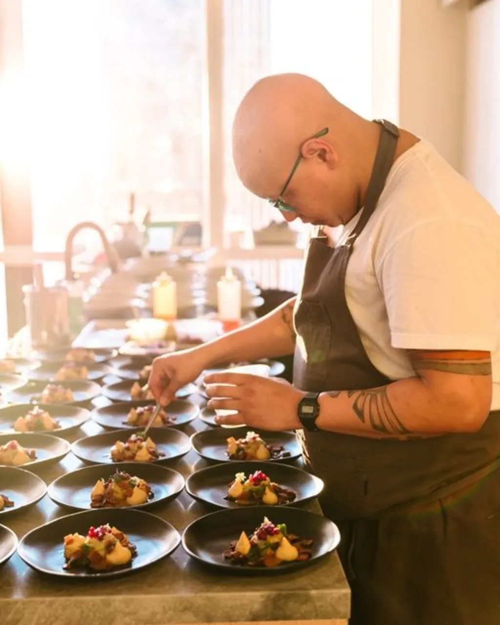 a chef smiling and standing infront of a table of people