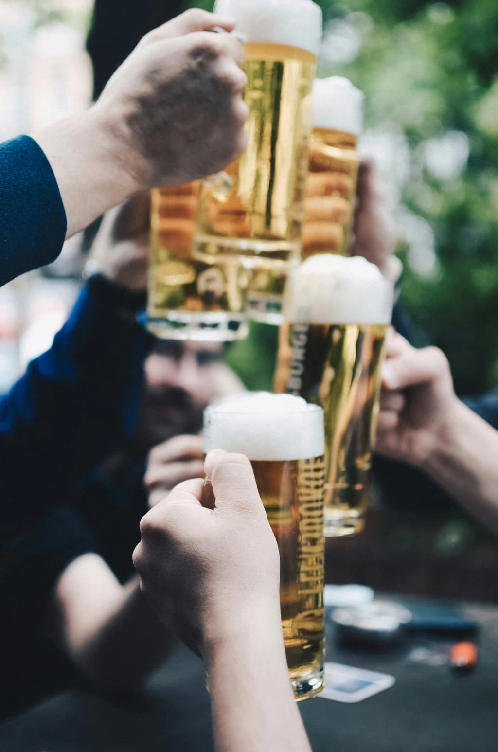 a close up of people cheersing different glasses of beer