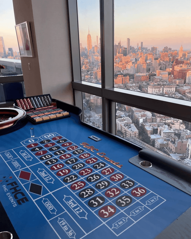 Roulette table with chips and a skyline view of NYC at sunset in the background.