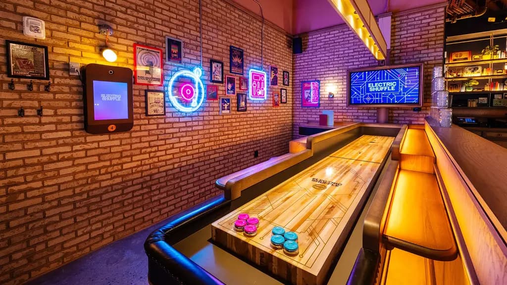 Brightly lit shuffleboard setup with neon signs and colorful decor, creating a lively and inviting atmosphere.