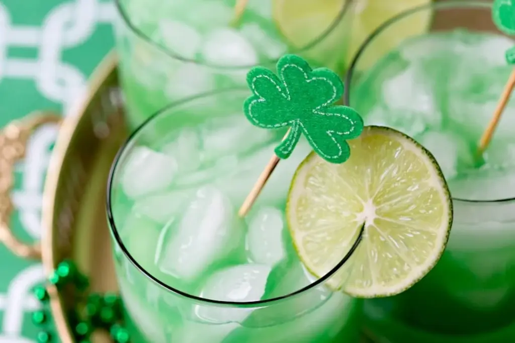 a green cocktail with a lime and a clover on top