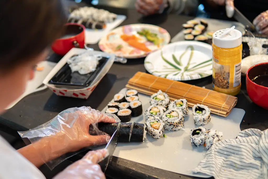 a chef preparing a sushi roll with ingredients around him