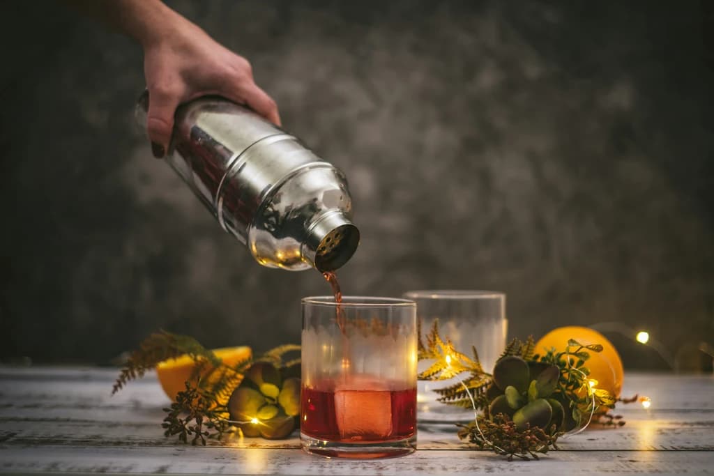 someone pouring a mixed drink into a glass