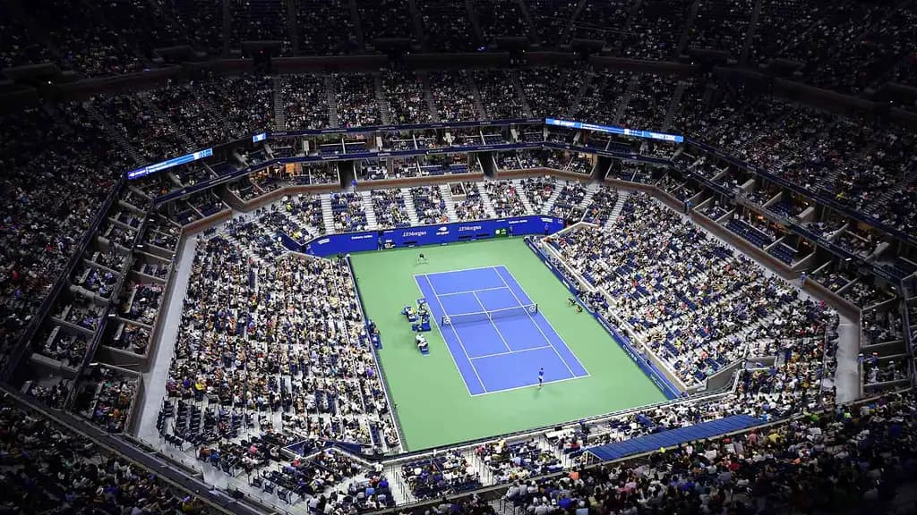 Aerial view of a tennis stadium during a match, showcasing the full crowd and the vibrant atmosphere of a high-profile event.
