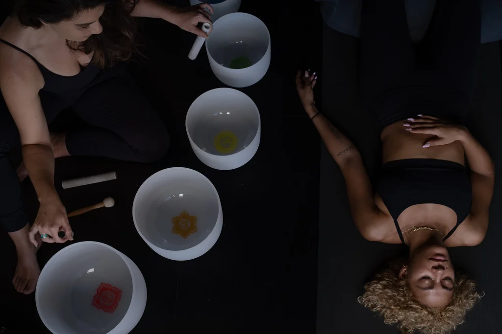 a person laying down with someone holding a sound bowl near them