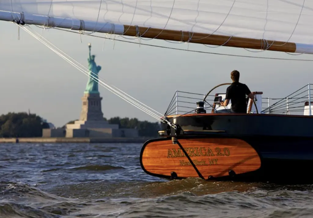 a close up of a sail boat with the statue of liberty in the background