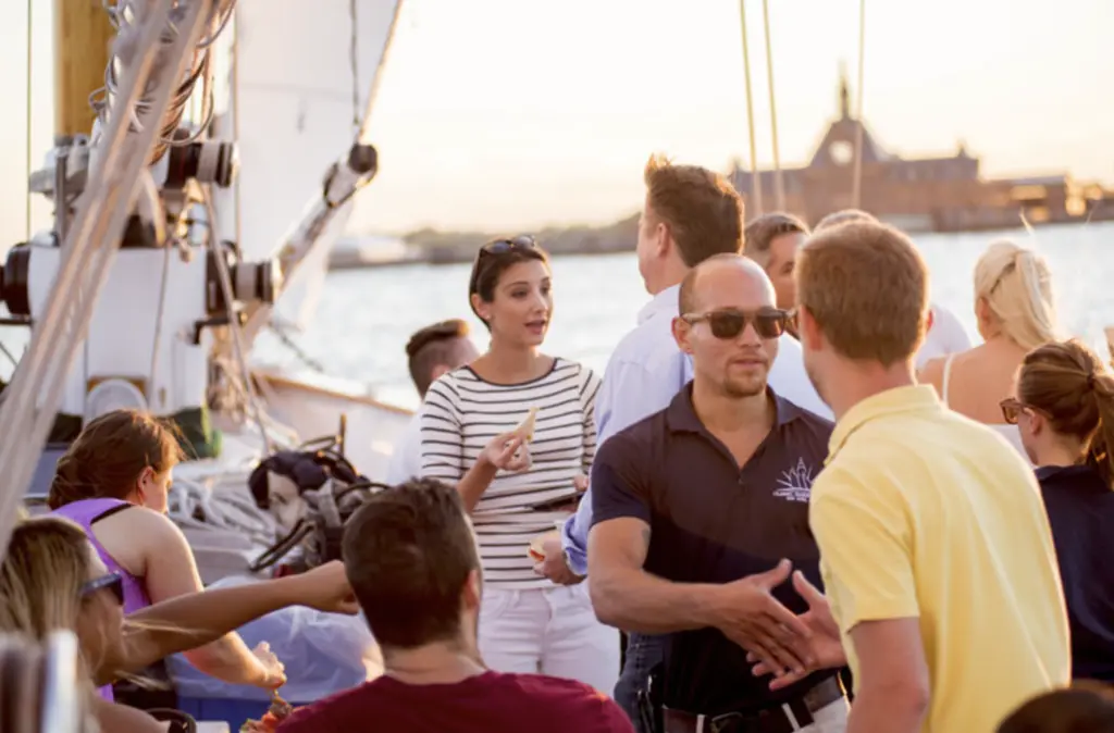 people on a sail boat, talking, eating, and drinking